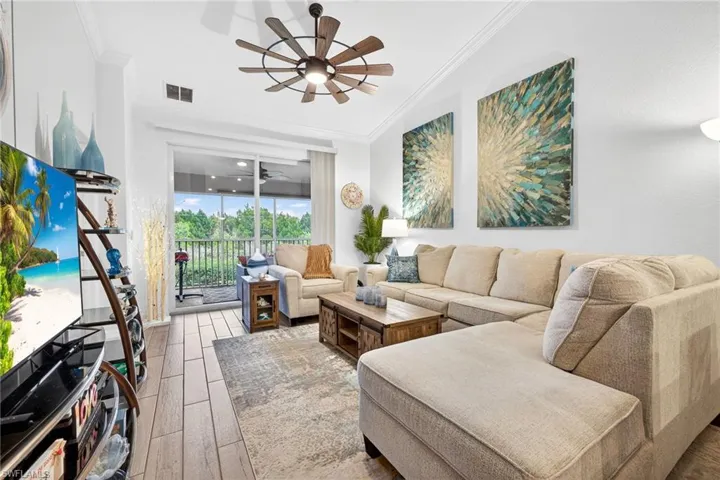 Living area featuring wood finished floors, crown molding, and ceiling fan
