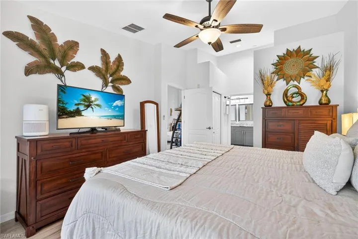 Bedroom featuring a high ceiling, wood finished floors, a ceiling fan, connected bathroom, and a closet
