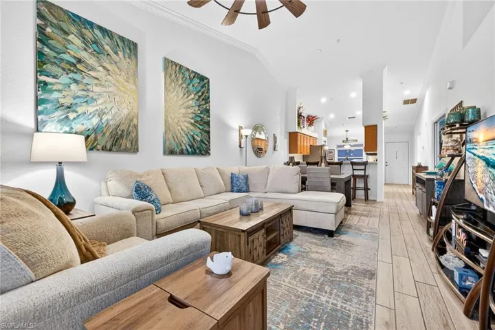 Living room featuring ceiling fan, light wood-style flooring, and ornamental molding