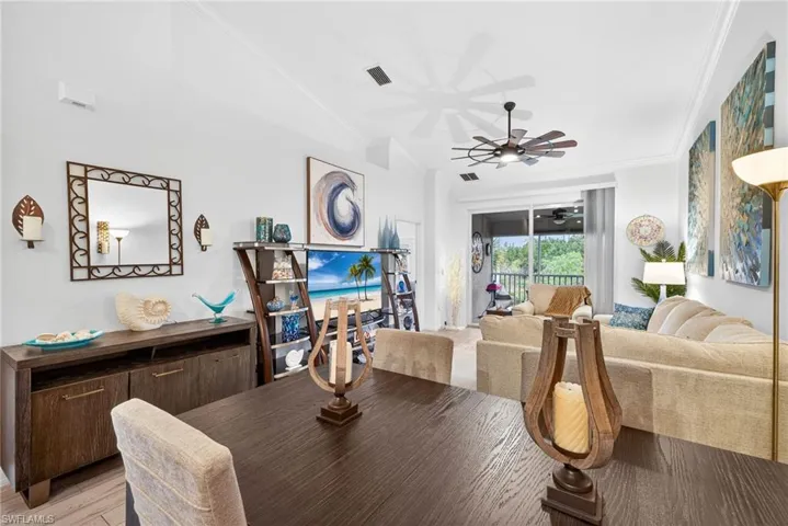 Dining room with ornamental molding, ceiling fan, lofted ceiling, and light wood-style floors