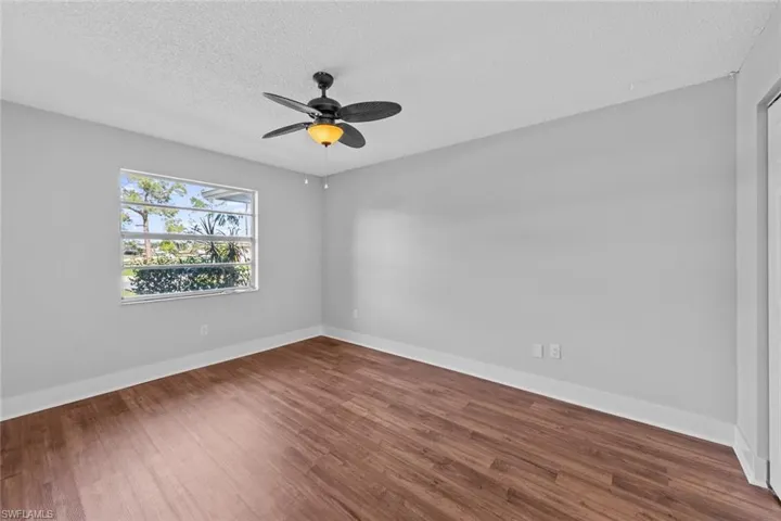 Empty room featuring hardwood / wood-style floors, ceiling fan, and a textured ceiling