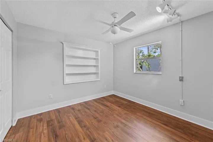 Spare room featuring a textured ceiling, hardwood / wood-style flooring, built in features, and ceiling fan