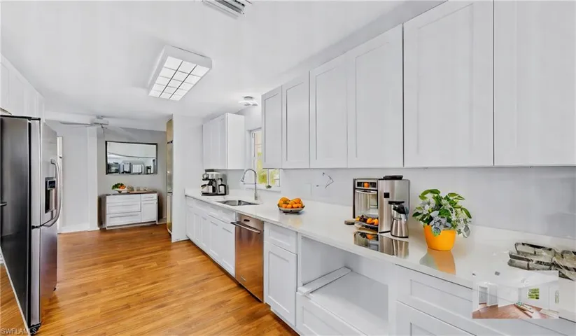 Kitchen with white cabinetry, stainless steel refrigerator with ice dispenser, and sink