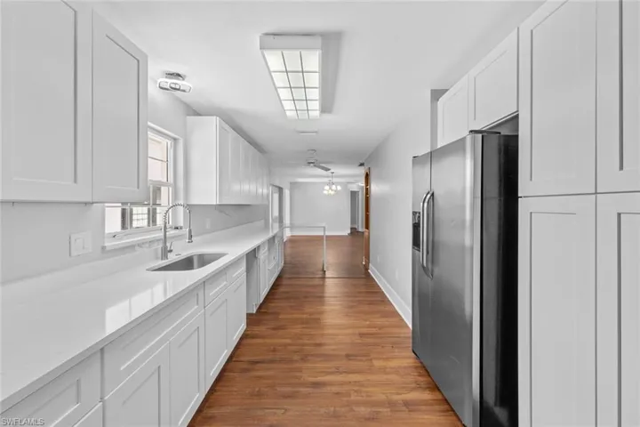 Kitchen with white cabinetry, sink, ceiling fan, stainless steel fridge with ice dispenser, and dark hardwood / wood-style flooring