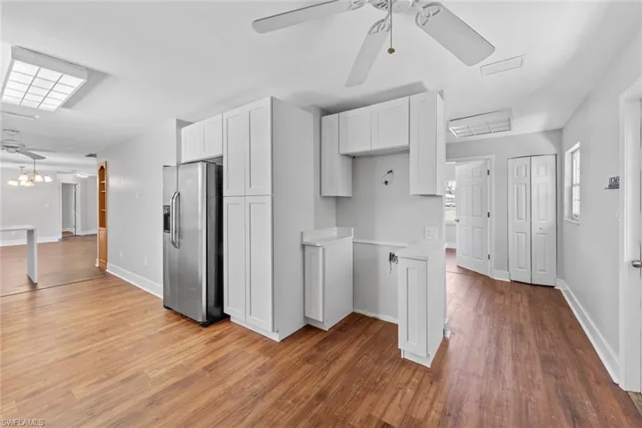 Kitchen featuring white cabinets, stainless steel fridge with ice dispenser, ceiling fan, and wood-type flooring