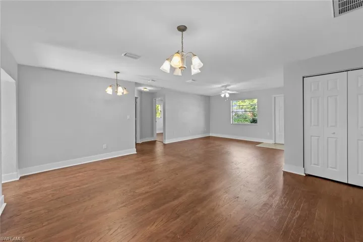 Unfurnished living room featuring dark wood-type flooring and ceiling fan with notable chandelier