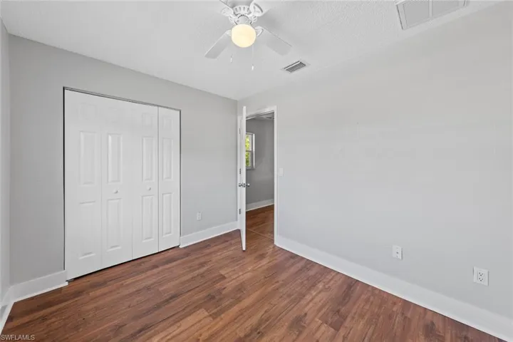 Unfurnished bedroom featuring a closet, a textured ceiling, dark hardwood / wood-style floors, and ceiling fan