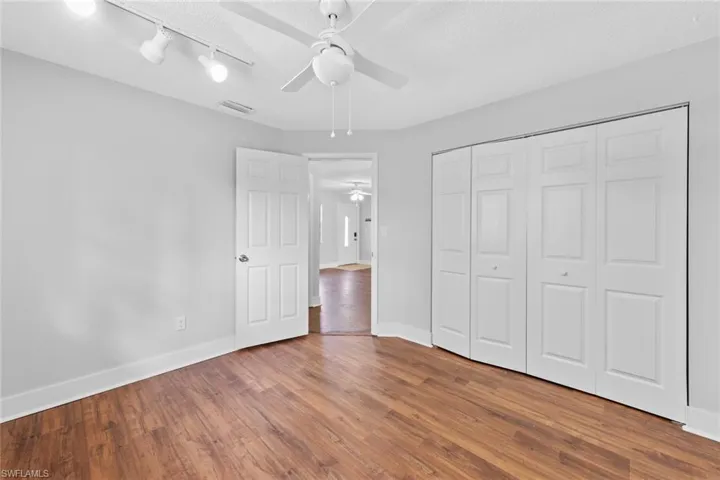 Unfurnished bedroom with ceiling fan, wood-type flooring, a textured ceiling, and a closet