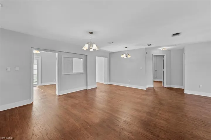 Unfurnished living room with dark wood-type flooring and an inviting chandelier