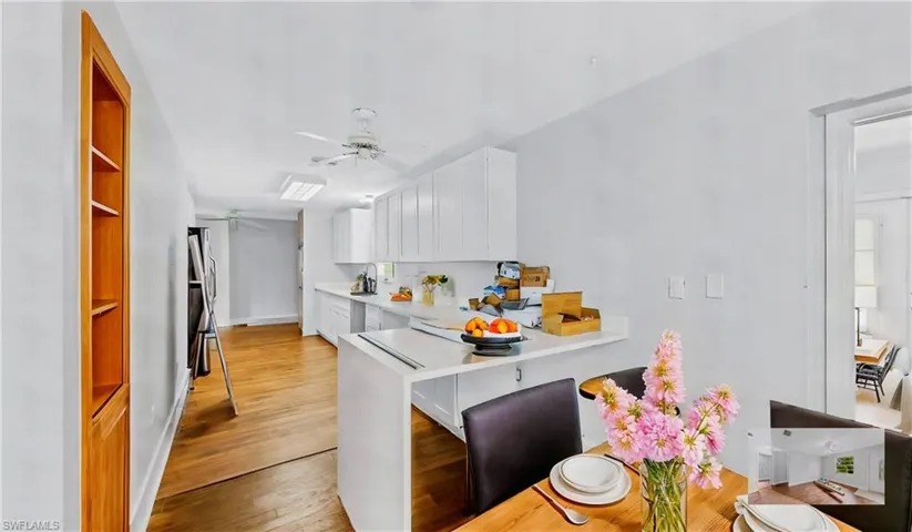 Kitchen featuring white cabinets, a kitchen bar, ceiling fan, kitchen peninsula, and light hardwood / wood-style flooring
