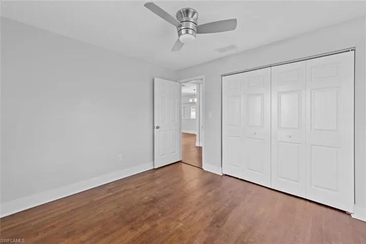 Unfurnished bedroom featuring a closet, dark hardwood / wood-style floors, and ceiling fan