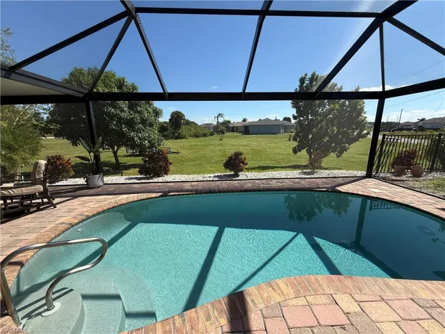 Outdoor pool featuring a sunroom, a lanai, and a lawn