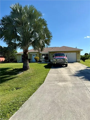 Ranch-style home with driveway, a front yard, a garage, and stucco siding