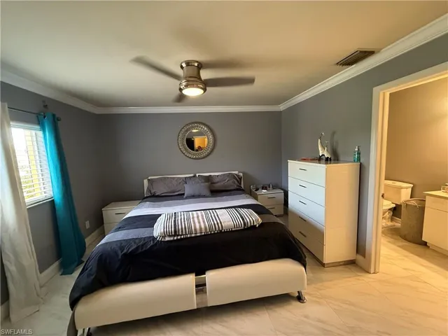 Bedroom featuring crown molding, a ceiling fan, and light marble finish flooring