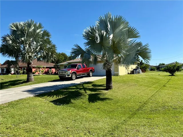View of grassy yard with concrete driveway
