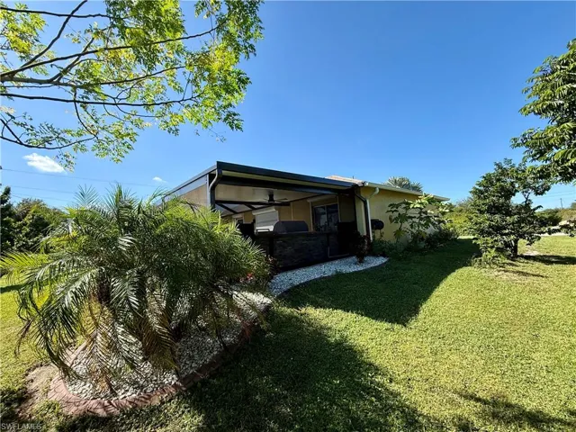 Back of property featuring stucco siding, a yard, and ceiling fan