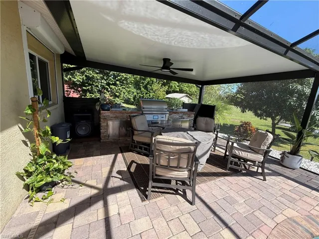 View of patio / terrace featuring a ceiling fan, an outdoor kitchen, and glass enclosure