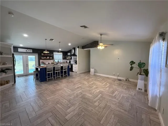 Kitchen featuring a kitchen bar, open shelves, light countertops, vaulted ceiling, and a kitchen island