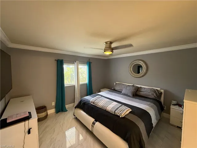 Bedroom featuring ornamental molding, light marble finish flooring, and ceiling fan