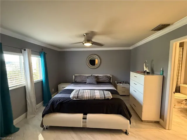 Bedroom featuring crown molding, a ceiling fan, and light marble finish flooring