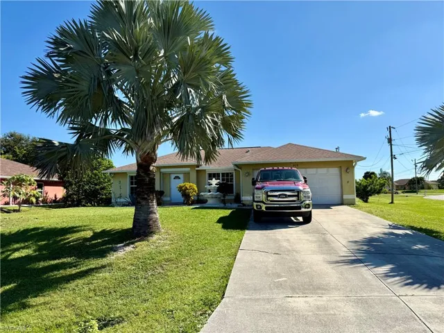 Single story home featuring a front yard, a garage, concrete driveway, and stucco siding
