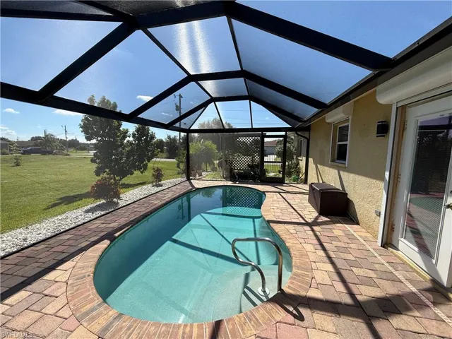 Swimming pool featuring a patio area, a sunroom, glass enclosure, and a lawn