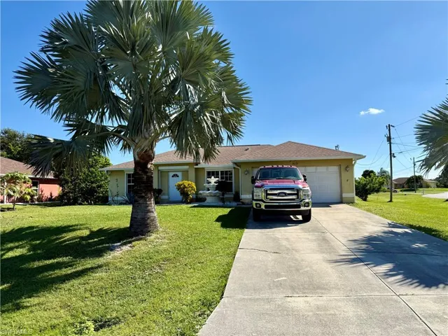Ranch-style home with a front lawn, an attached garage, driveway, and stucco siding