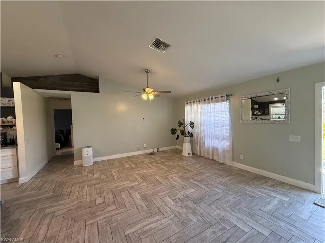 Empty room with lofted ceiling and a ceiling fan