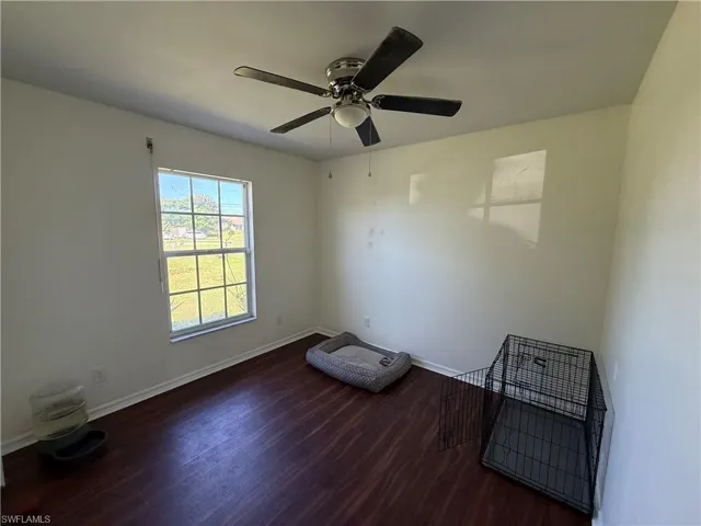 Empty room with dark wood-style flooring and a ceiling fan