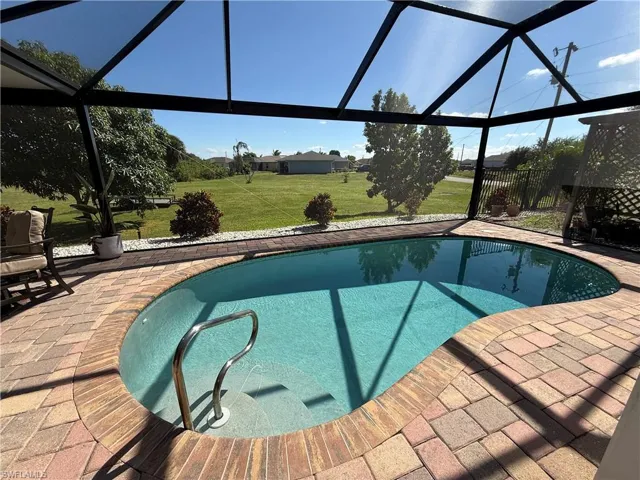 Outdoor pool featuring a sunroom, glass enclosure, and a lawn