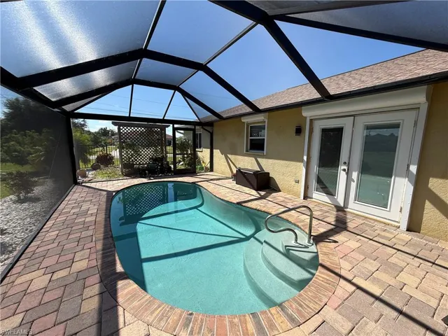 Swimming pool featuring a patio area, a sunroom, a lanai, and french doors