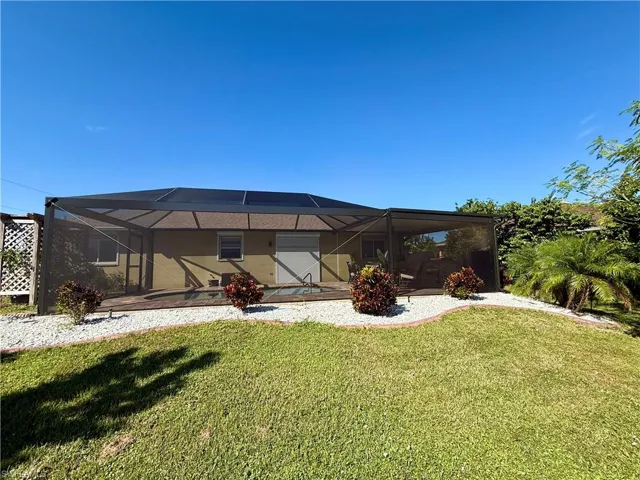 Back of property featuring a sunroom, glass enclosure, and a lawn