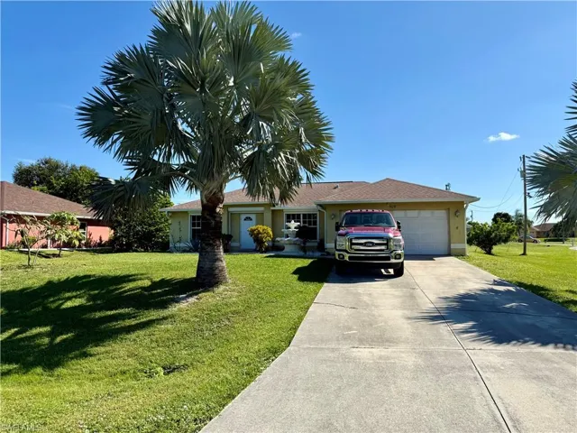 Ranch-style house with a front lawn, an attached garage, driveway, and stucco siding