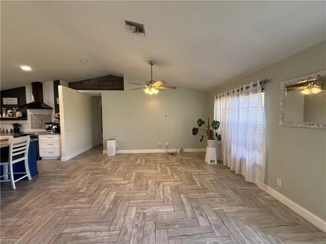Unfurnished living room featuring vaulted ceiling and ceiling fan