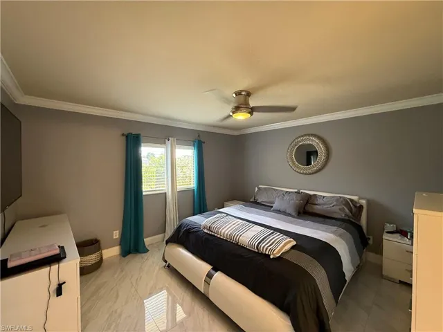 Bedroom featuring ornamental molding, a ceiling fan, and light marble finish floors