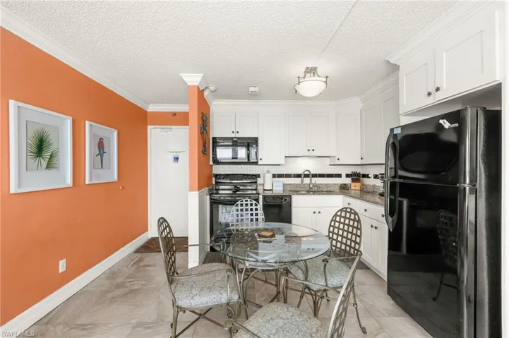 Kitchen featuring black appliances, white cabinets, dark stone counters, crown molding, and backsplash