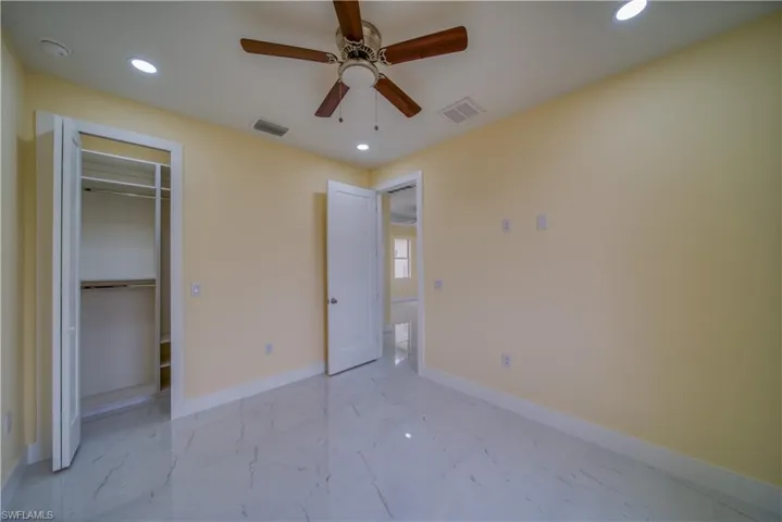Unfurnished bedroom with ceiling fan and a closet