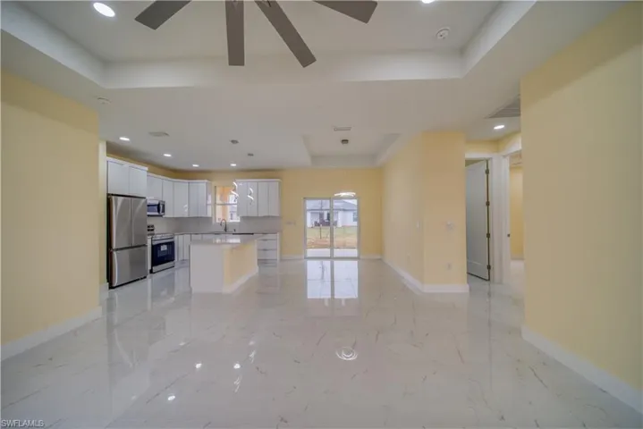 Kitchen featuring pendant lighting, appliances with stainless steel finishes, white cabinets, a tray ceiling, and a center island