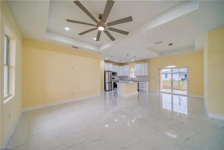 Unfurnished living room with sink, ceiling fan, and a raised ceiling