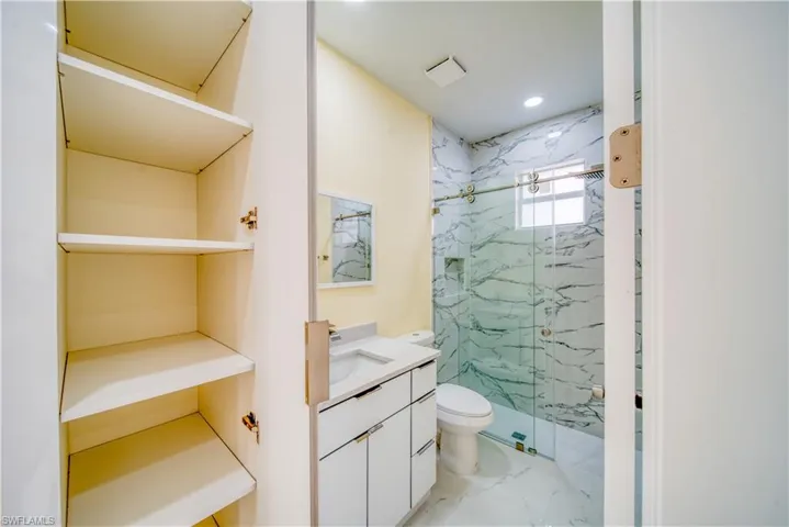 Bathroom with a shower with door, toilet, and vanity