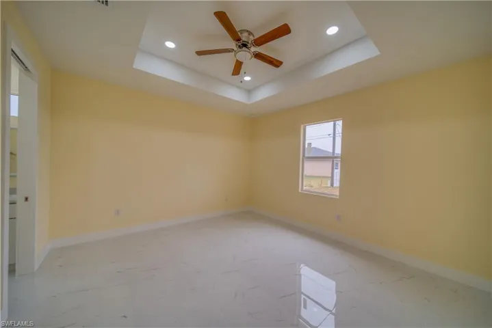Unfurnished room with ceiling fan and a tray ceiling