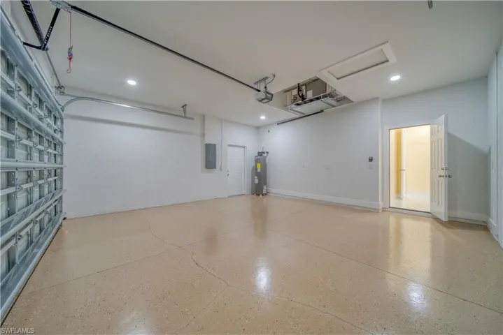 Garage featuring a garage door opener, electric panel, and electric water heater