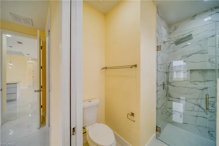 Bathroom featuring a shower with shower door and toilet
