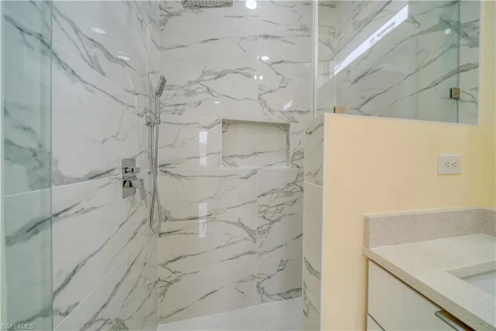 Bathroom featuring tiled shower and vanity