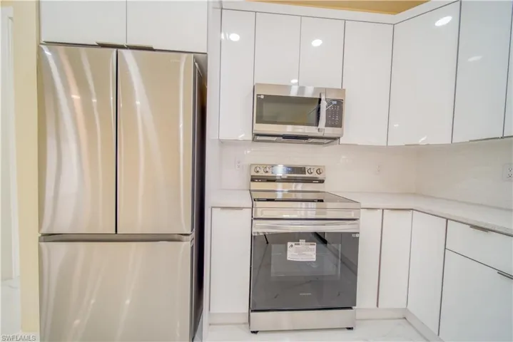 Kitchen featuring decorative backsplash, white cabinetry, and stainless steel appliances