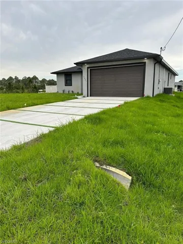 View of front facade featuring a garage, central AC, and a front yard