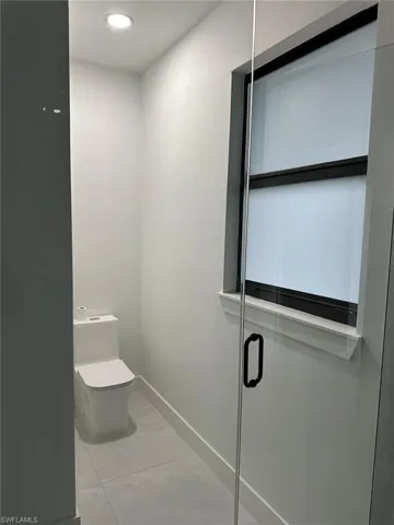 Bathroom featuring walk in shower, tile flooring, and toilet