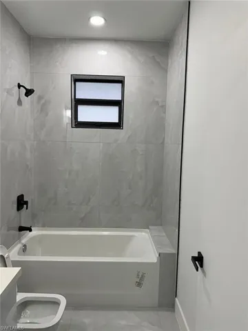 Full bathroom with tiled shower / bath, tile flooring, toilet, and vanity