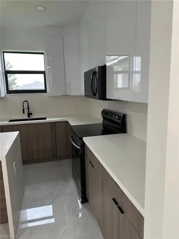Kitchen with black appliances, sink, and light tile flooring