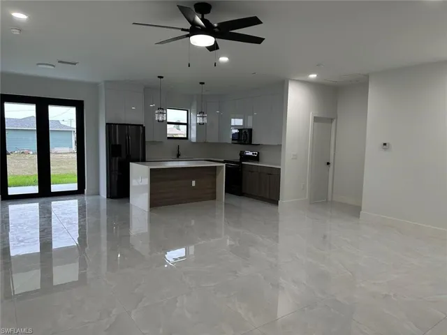 Kitchen with electric range, a center island, light tile flooring, and refrigerator with ice dispenser